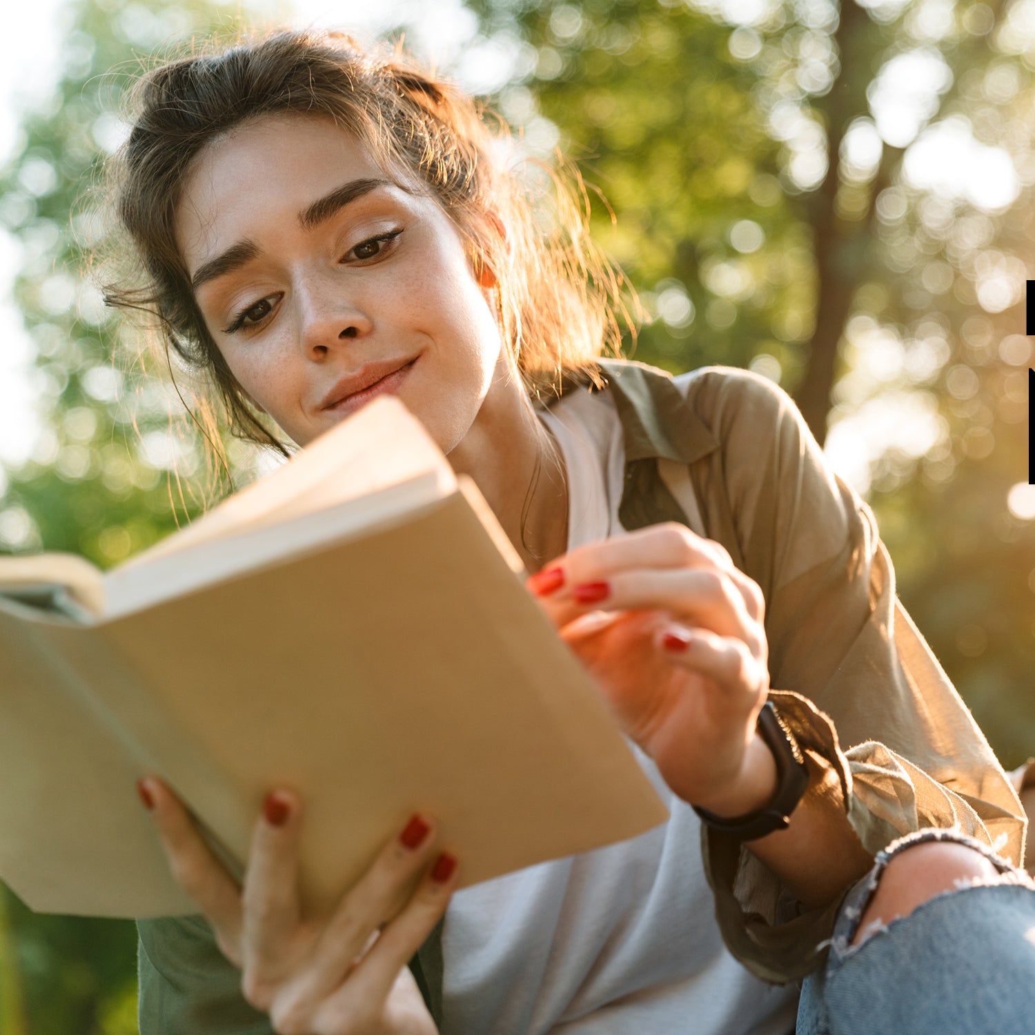 Eine dunkelhaarige Frau liest ein Ratgeber-Buch von KOSMOS draußen im Grünen bei Sonnenschein.